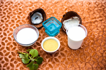 Close up of hair remedy to nourish hair naturally on brown colored fabric surface i.e. Coconut milk with curd mixed well along with some fresh leaves of ajwain plant for decoration.