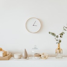 Modern Interior Design Concept. Bright Beige And Golden Apartment With Clock, Eucalyptus Branch, Vase, Candle.