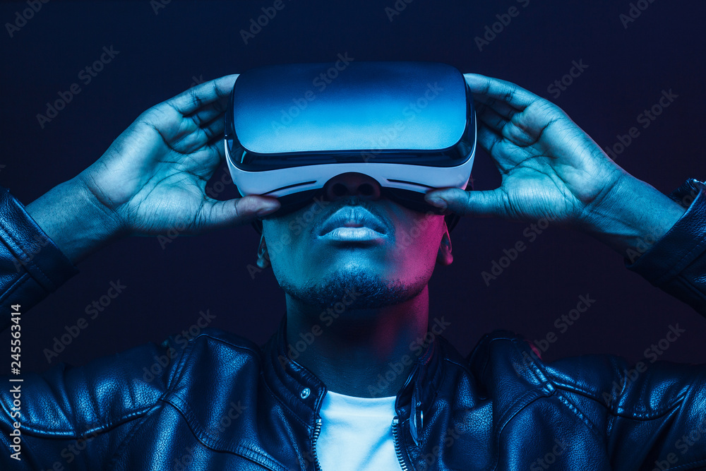 Portrait of African guy isolated on black background wearing headset of virtual reality - obrazy, fototapety, plakaty 