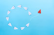 © Worawut - Group of white paper planes fly in a circle and one red paper plane pointing in different way on blue background. Business for new ideas creativity, innovative and solution concept.