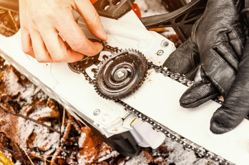 Sticker - Hands a man puts on a chainsaw on the tooth wheel of an electric saw. Woodcutter mechanics, equipment.