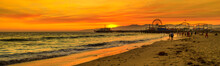 Scenic Landscape Of Iconic Santa Monica Pier At Orange Sunset Sky From The Beach On Paficif Ocean. Santa Monica Historic Landmark, California, USA. Wide Banner Panorama.