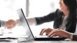 © yurolaitsalbert - businessman working on laptop on the background of handshake of business partners