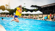 © Med Photo Studio - a 6-year blond boy in a life vest jumping in the swimming pool of a hotel in Turkey