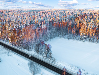 Wall Mural - Aerial view of a car on winter road in the forest. Winter landscape. Aerial photography of snowy forest with a car on the road. Captured from above with a drone. Aerial photo. Car in motion