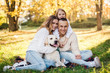 © zadorozhna - Happy beautiful family with dog labrador is having fun  are sitting on green grass in park.