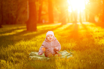 Baby in the park in the rays of sunset. Toddler on the nature outdoors. Backlight. Summertime family  scene