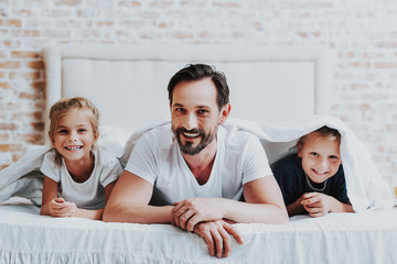 Wall Mural - Smiling parent and two kids laying on bed