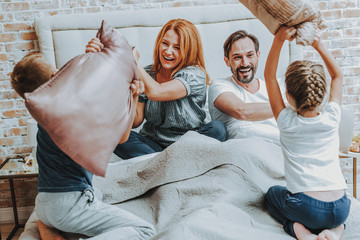 Wall Mural - Happy family fighting by pillow together in bed