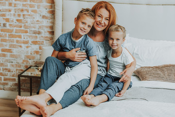 Wall Mural - Happy mom and two kids relaxing in bed