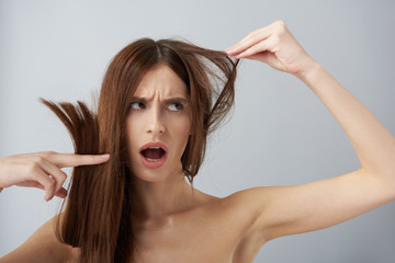 Wall Mural - Shocked girl with naked shoulders demonstrating her damaged hair