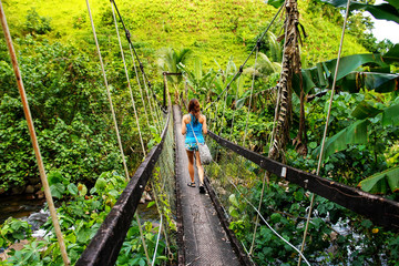 Wall Mural - Young woman walking on suspension bridge over Wainibau stream, Lavena Coastal Walk, Taveuni Island, Fiji