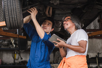 Two mechanic engineer repair the car and checklist fix item with tablet in the garage  - Image