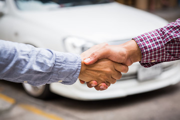 Shaking hands on car background.