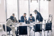 © alfa27 - Multicultural business partners meeting discussing, using internet, and documents with graphs and charts, collaborating vively over panoramic windows backgrounds
