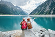 Leinwandbild Motiv Travelers couple look at the mountain lake. Travel and active life concept with team. Adventure and travel in the mountains region in the Austria. Travel - image