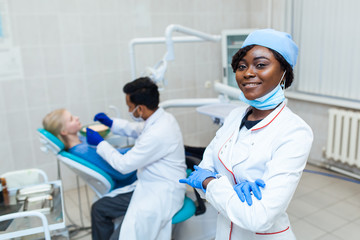 Wall Mural - Portrait of female black dentist in dental office. She standing at her office and she has beautiful smile.