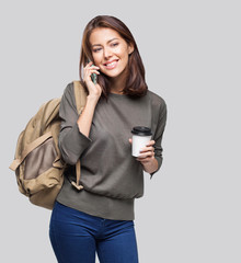 Wall Mural - Young beautiful girl with a cup of coffee talking on mobile phone