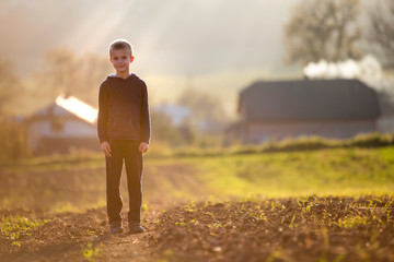 young blond serious tired child boy standing alone on field after harvest on late summer or autumn s