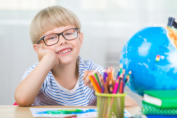 Cute little boy study. Child with books and globe learning lesons. Schoolboy studying. Adorable caucasian boy doing homework.