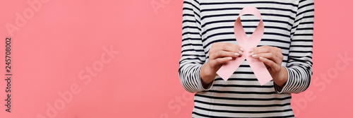 Fotografía Midsection of a young woman holding pink breast cancer awareness ribbon isolated over living coral background