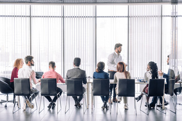 Diverse people sitting in a line at conference hall at corporate briefing, african and caucasian businessmen and businesswomen partners team attending training concept, Backside panoramic view