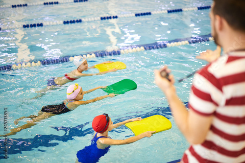 Dekoracja na wymiar  grupa-malych-dziewczynek-uczacych-sie-plywania-z-deskami-podczas-szkolenia-instruktorow-plywania