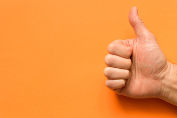 The hand of a man with his thumb up. On an orange background. Empty text space.