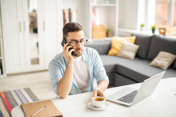 Wall Mural - Serious businessman with smartphone going to have a cup of coffee while calling client or colleague by workplace