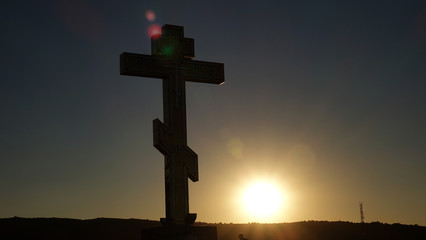 The symbol of the Christian and the Catholic Church: a silhouette of a cross against the sunset