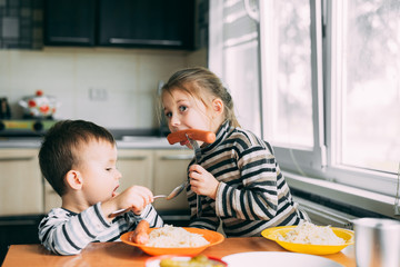 Wall Mural - Children boy eating in the kitchen sausage and pasta