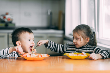 Wall Mural - Boy and girl in the kitchen eating pasta very hungry