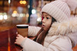 Cute happy little girl drinks hot tea in a street cafe