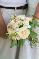 Wall Mural - the bride is holding a pink and beige wedding bouquet of fresh flowers and eucalyptus