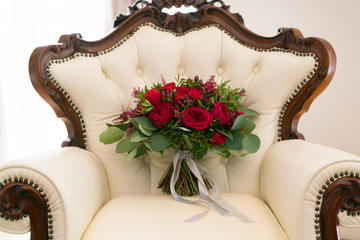 Wall Mural - bright red wedding bouquet of fresh flowers and eucalyptus stands on the armchair