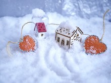 Two Small Toy Houses With Lighted Illumination And A Pair Of Orange Hearts Of Felt On The Snow, The Concept Of Seasonal Winter Holidays, Valentines Day, Christmas