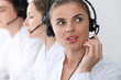 © rogerphoto - Call center operators at work. Focus at beautiful business woman in headset