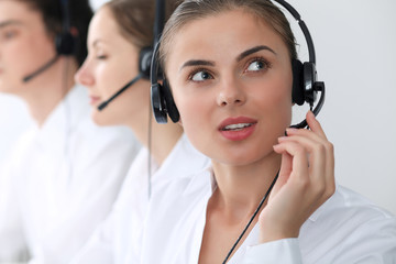 Wall Mural - Call center operators at work. Focus at beautiful business woman in headset