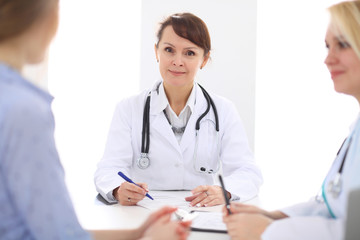 Happy smiling female patient with two cheerful doctors in the background. 