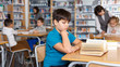 © JackF - Tween boy reading textbooks in school library