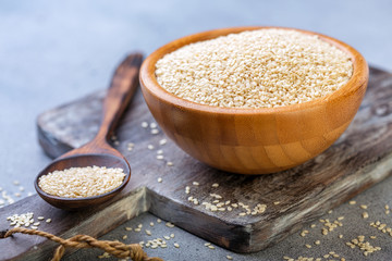 Canvas Print - White sesame seeds in a wooden bowl and spoon.