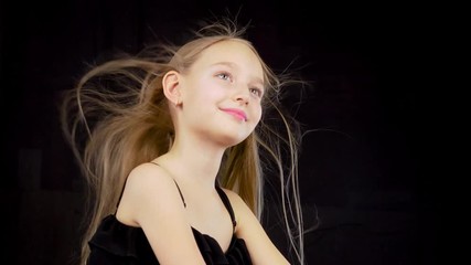 cute girl with fluttering hair. close up little model girl with fluttering hair isolated on black ba