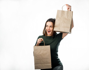 Poster - Happy beautiful woman raising shopping bags in every hand while looking away. Shopping and fashion concept. Isolated front view on white background.