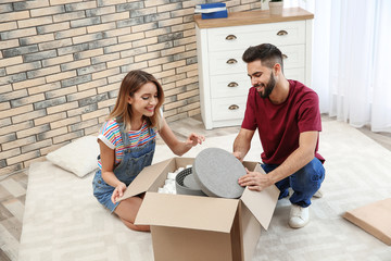 Wall Mural - Young couple opening parcel on floor at home