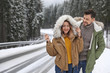 © New Africa - Couple walking near snowy forest, space for text. Winter vacation
