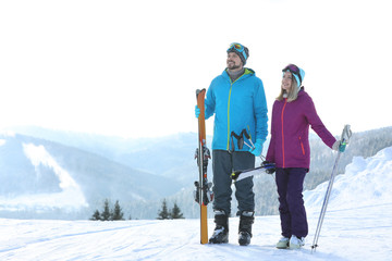 Canvas Print - Happy couple with ski equipment spending winter vacation in mountains. Space for text