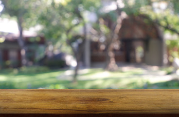 Empty wooden table in front of abstract blurred green of garden and house background. For montage product display or design key visual layout - Image.