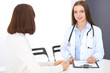 © rogerphoto - Doctor and  patient  discussing something while standing near reception desk in emergency hospital. Physician at work in clinic. Medicine and health care concept
