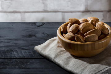 Wall Mural - Almonds with shell in wooden bowls on slate background