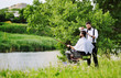 © Evgeniy Kalinovskiy - a professional hairdresser or Barber cuts the hair of a client in a Barber chair with a fishing rod in his hands on the background of greenery, trees, river and Park. Barbershop outdoors